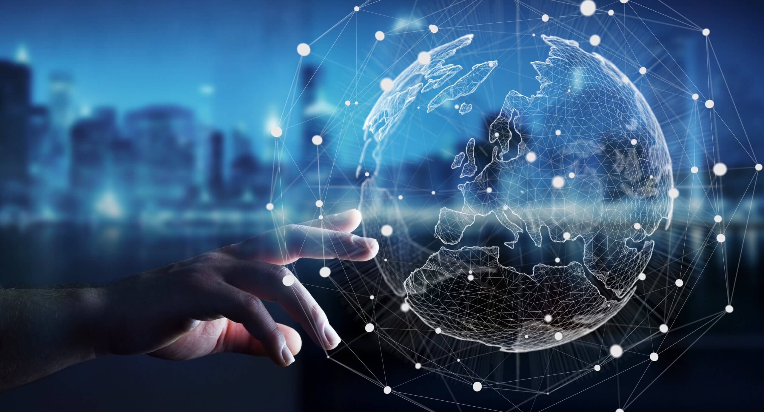 A hand reaches toward a digital, wireframe globe with connected dots, symbolizing global networks and technology, with a blurred cityscape in the background.